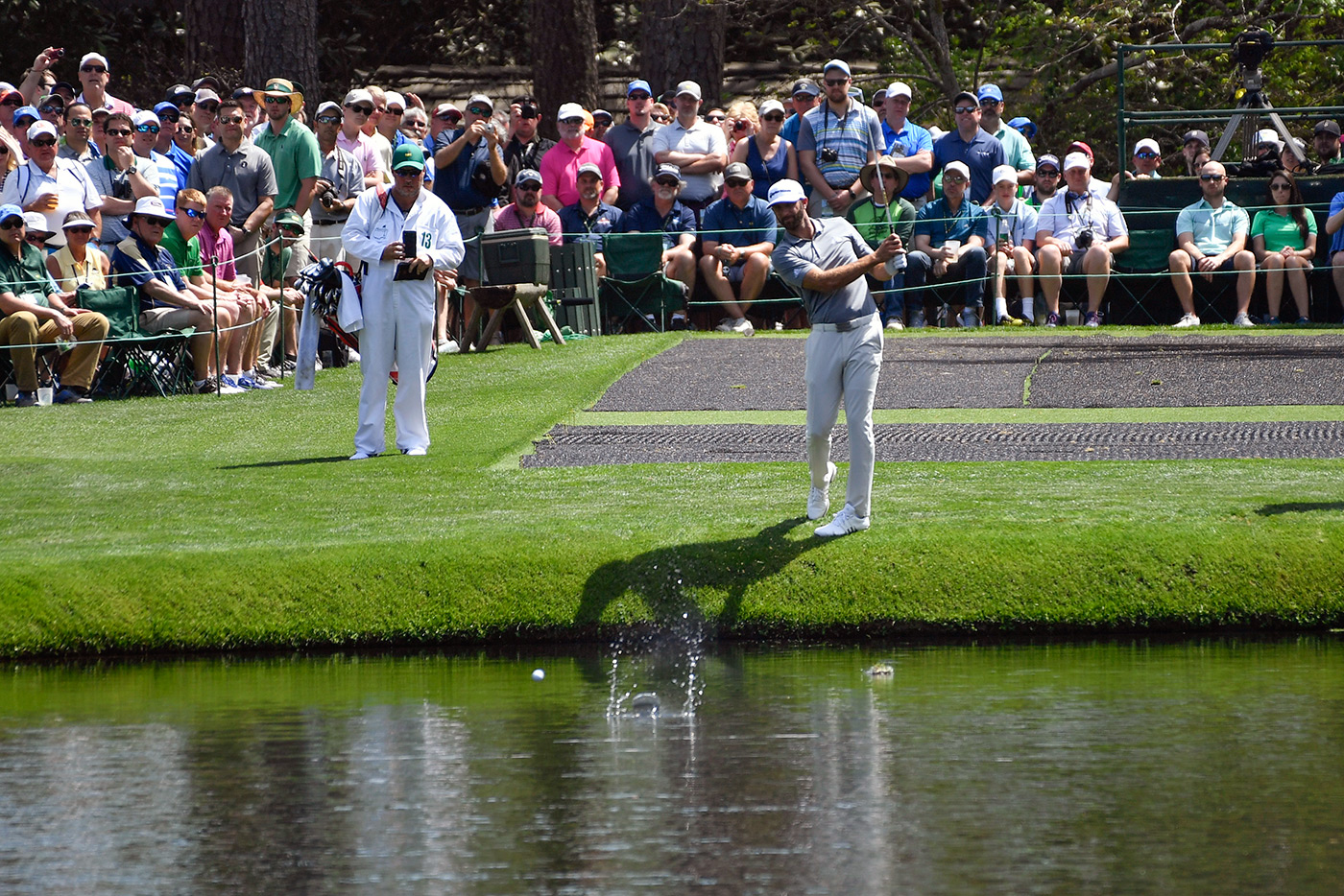 Dustin Johnson skips a shot across the pond at No. 16 during a Masters practice round.
